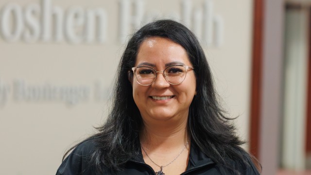 Smiling woman standing in front of a wall accepting an award