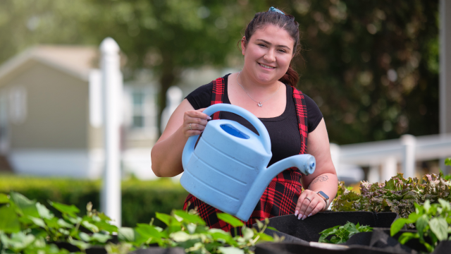 Woman smiling while watering plants