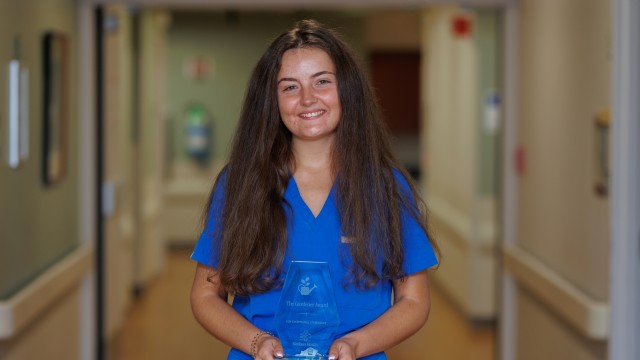 Woman with long hair smiling while holding an award