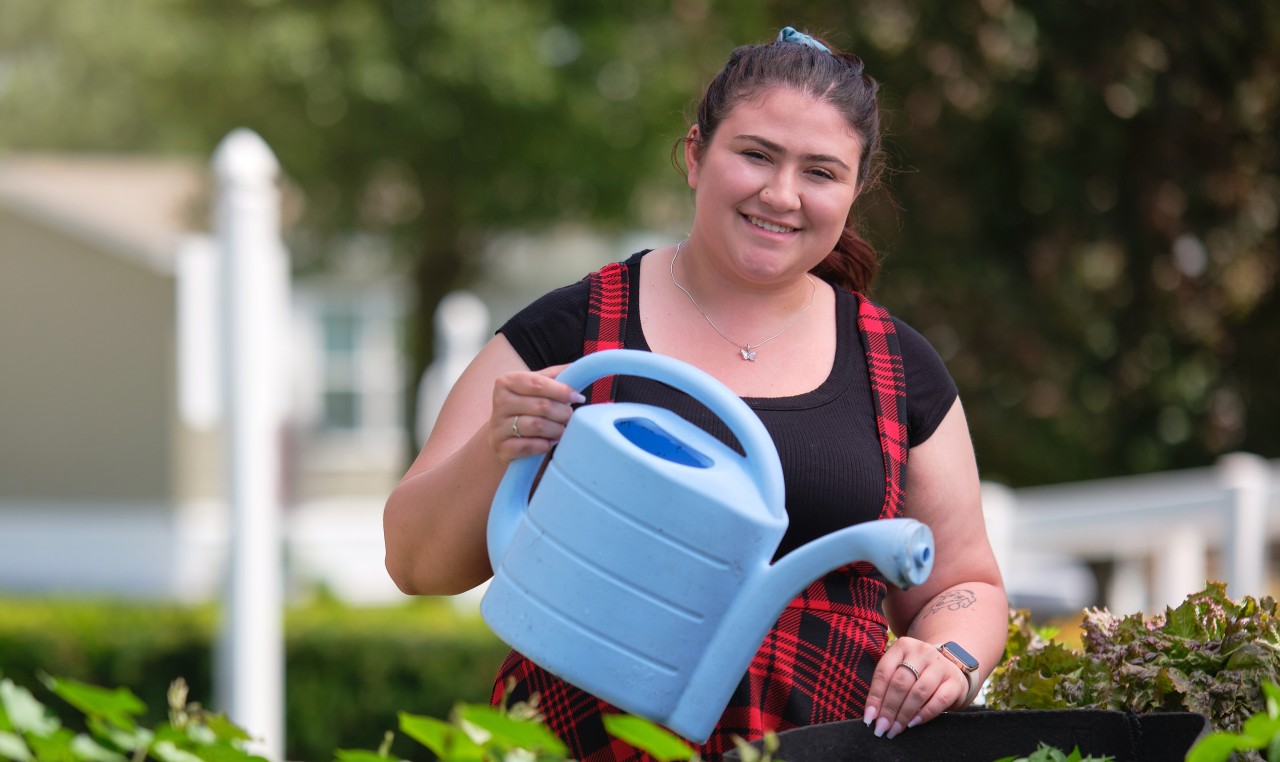 Woman watering plants with a blue watering can v2