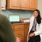 Doctor sitting in an exam room showing a computer screen to a patient