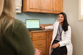 Doctor sitting in an exam room showing a computer screen to a patient
