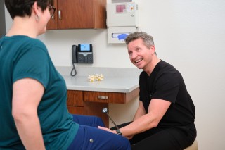 Doctor smiling at patient while examining her knee