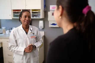 Doctor standing in exam room smiling at patient