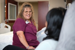 Nurse smiling at a patient while sitting at the bedside