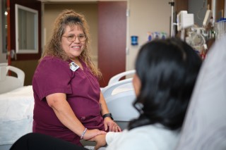 Nursing assistant sitting at the bedside of a patient