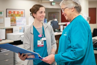 Two nurses standing while reviewing a chart
