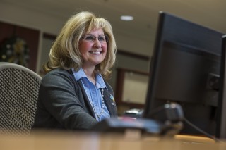 Woman wearing glasses sitting at a computer smiling