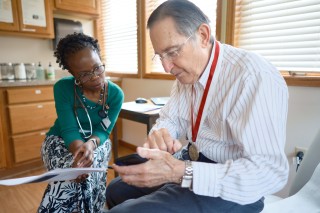 Doctor and patient sitting in an exam room looking at a phone