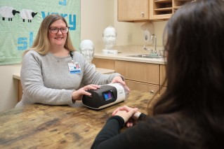 Doctor sitting with a device on the table, smiling at a patient