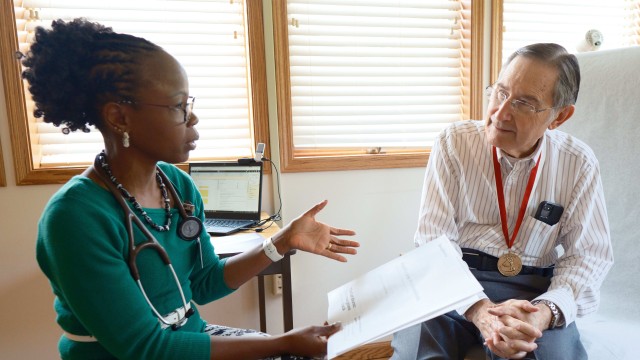 Doctor sitting on chair while discussing care with a patient
