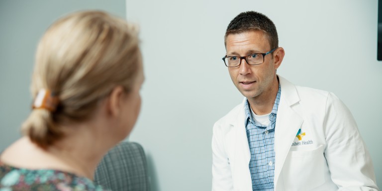 Doctor showing a patient a paper while sitting in an office
