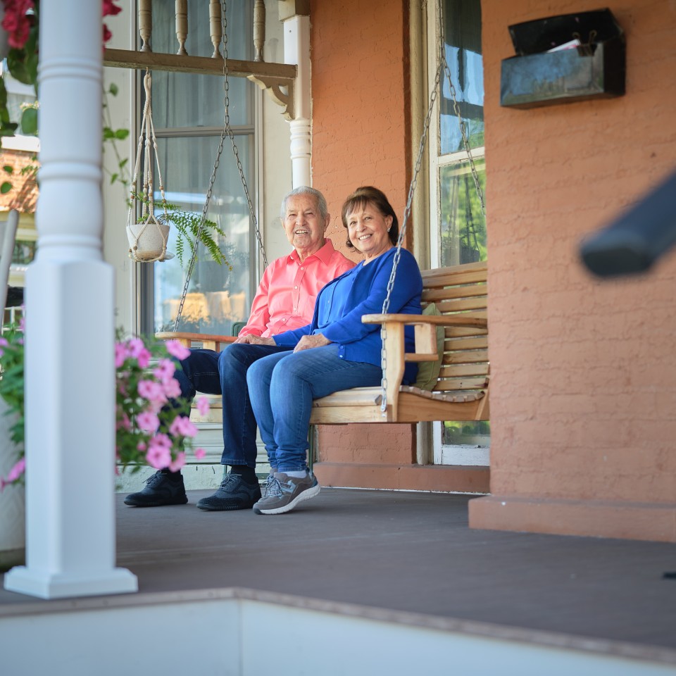 Man and Woman Smiling Sitting on Porch Swing
