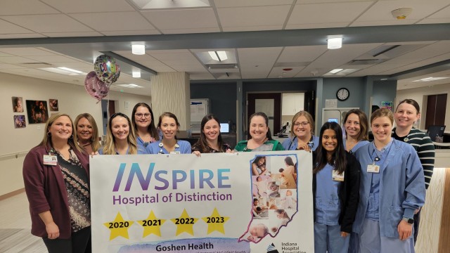 Group of smiling women standing around an award sign